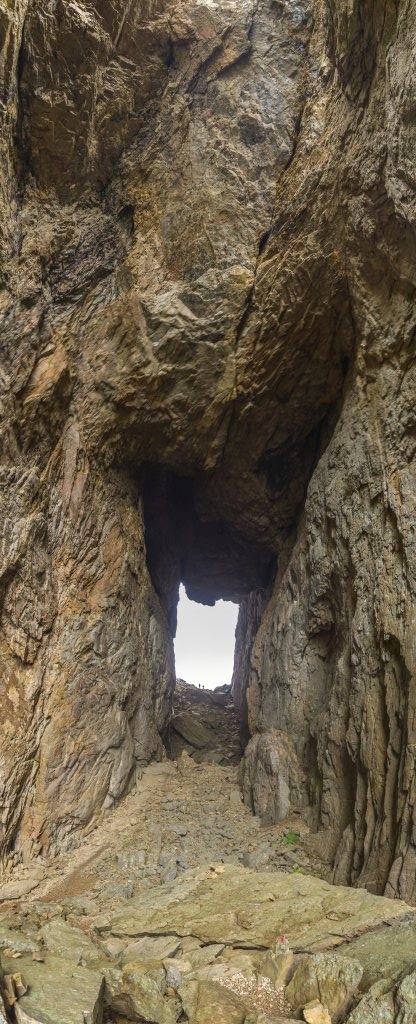 Vertikalpanorama vom etwa 35 Meter hohen und rund 160 Meter langen Riesen-Felsenloch im Gipfel des Torghatten (258m) auf der Insel Torget in der Nähe von Bronnoysund, Norwegen, Juli 2022.