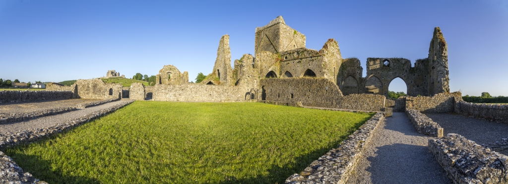 Bei Sonnenuntergang an der Cashel Hore Abbey aus dem 13. Jh. mit dem Irischen Wahrzeichen des Rock of Cashel im Hintergrund, Irland, Juni 2023.