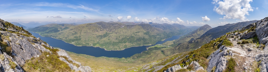 Am Gipfel des Pap of Glencoe / Sgorr Na Ciche (742m) mit Blick auf den tief eingeschnittenen Loch Leven sowie die gegenüber liegenden Tom Medhoin (621m), Mam Na Gualainn (796m) und Garbh Bheinn (867m), Schottland, Mai 2024.