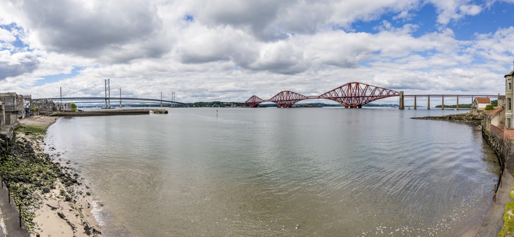 Firth of Forth bei South Queensferry mit den mittlerweile zwei Highway-Brücken und der historischen roten Metallkonstruktion der Eisenbahn-Ausleger-Brücke nach Edinburgh aus dem Jahr 1890 mit einer Spannweite von 2523m und einer Höhe von 46m, Schottland, Juni 2024.