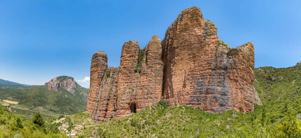 Die beeindruckende Felsengruppe der Mallos de Riglos erhebt sich steil &uuml;ber dem Ort Riglos mit seiner &uuml;ber 400 Jahre alten kleinen Kirche kleine Kirche Iglesia de Nuestra Senora del Mallo, Nordspanien, Mai 2025.